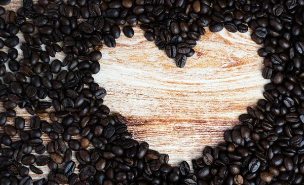 Scattered coffee beans in the shape of a heart. Coffee day. Place for text. Top view. Selective focus.