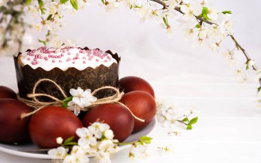 Easter spring composition with Easter cake, colored eggs and cherry branches. Close-up. Copy space. Selective focus.