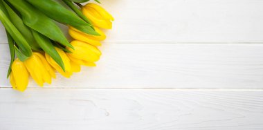 Bouquet of beautiful yellow tulips on a white wooden background. Banner. Place for text. Top view. Flatlay. Selective focus.
