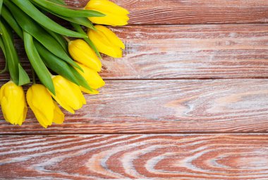 Spring composition with bouquet of yellow tulips on a wooden background. Top view. Copy space. Selective focus.