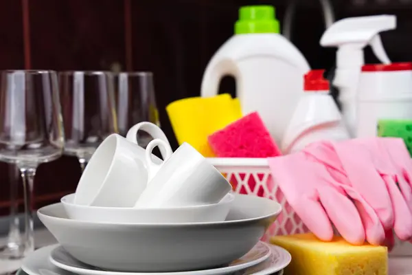 Clean dishes and detergents and cleaning products on the table in the kitchen. Cleaning service concept. Close-up. Selective focus.