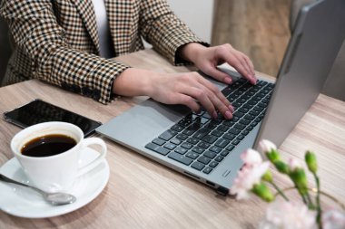 Masada dizüstü bilgisayarda çalışan genç bir kadının elleri. Yakın plan. Seçici odak.