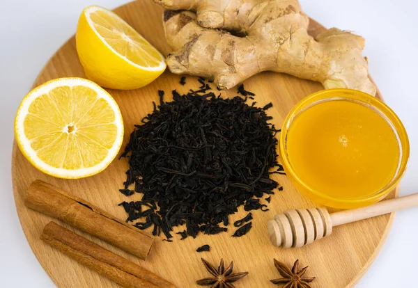 A black tea, ginger, lemon, honey and cinnamon on wooden background. Tea drinking concept. Top view. Close-up. Selective focus.