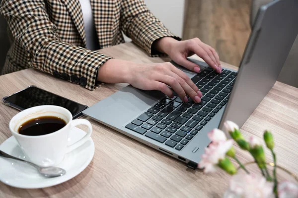 Masada dizüstü bilgisayarda çalışan genç bir kadının elleri. Yakın plan. Seçici odak.