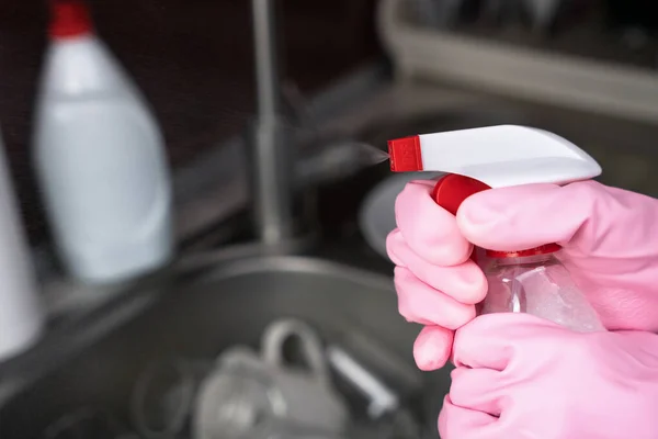Woman in rubber gloves sprays cleaner. House cleaning concept. Close-up. Place for text. Selective focus.