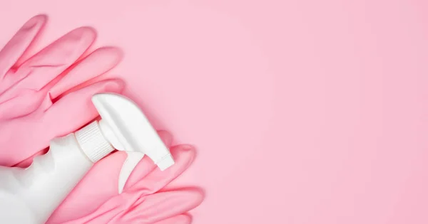 Pink rubber gloves and spray cleaner on a pink background. Flatlay. Banner. Close-up. Top view. Place for text.