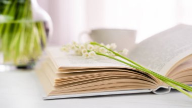 Açık kitap ve vadi zambakları. Bahar kompozisyonu. Seçici odak.