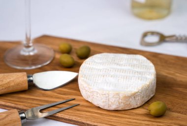 Lezzetli Camembert peyniri, zeytin ve ahşap bir tahtanın üzerinde şarap kadehi. Yakın plan. Seçici odak.