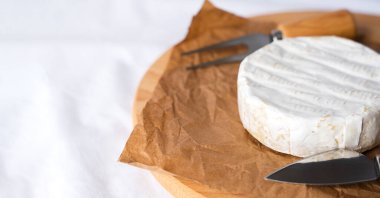 Fransız yumuşak peyniri, beyaz peynirli krema, masada çatal ve bıçak. Kahvaltı konsepti. Yakın plan. Uzayı kopyala Seçici odak.