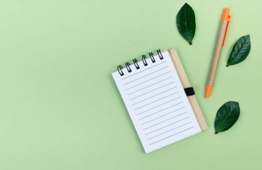 Yeşil arka planda geri dönüştürülmüş kağıt kalemli not defteri. Üst Manzara. Pankart. Boşluğu kopyala.