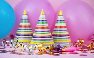 Renkli parti şapkaları, balonlar, pembe arka planda doğum günü partisi için konfeti. Yakın plan..