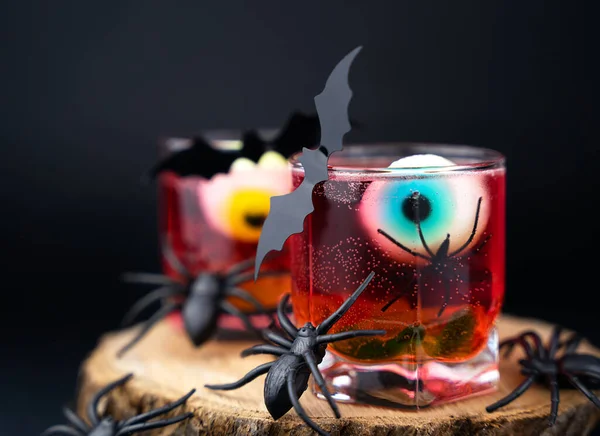 Gözleri, solucanları, yarasaları ve siyah arka planda örümcekleri olan ürkütücü kırmızı bir kokteyl. Mutlu Cadılar Bayramı. Yakın plan. Seçici odak.