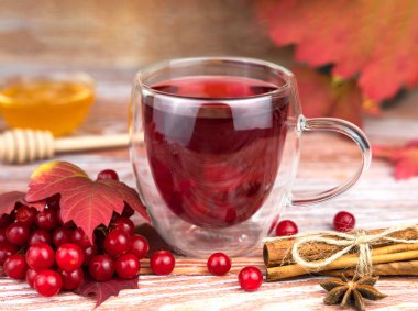 Tahta bir masanın üzerinde tarçınlı ve ballı Viburnum böğürtlenlerinden çay. Yakın plan. Seçici odak.