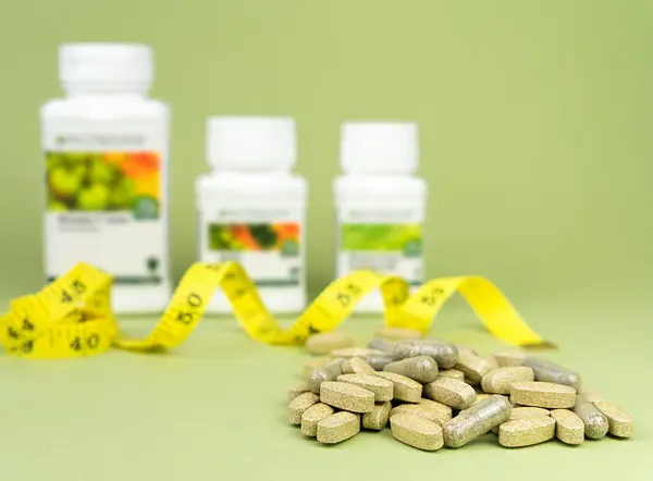 Sports nutrition, supplements. Natural vitamins and supplements on a green background. Close-up. Selective focus.