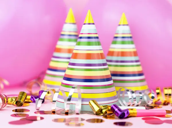Colorful party hats, pink balloons, confetti for party on pink background. Close-up.