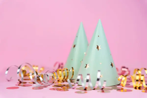 Party hats with the stars and festive decor on a pink background. Copy space. Close-up.