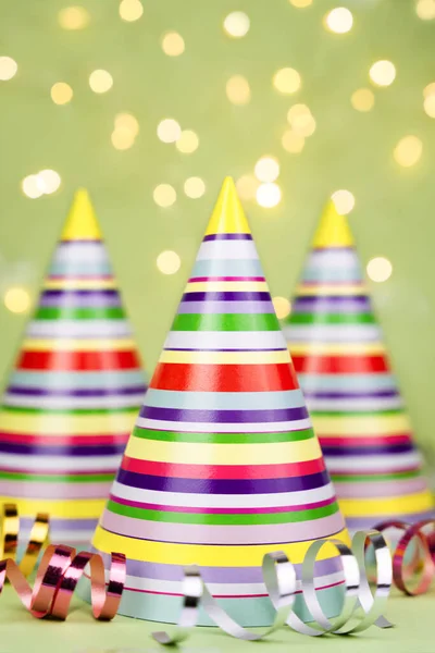 Striped colored party hats on green background. Holiday party. Close-up.