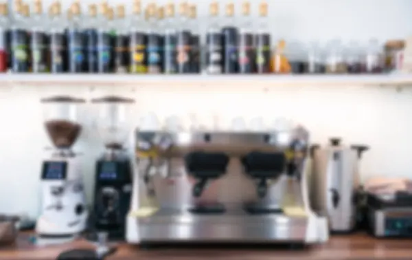 Blurred coffee shop interior with coffee machine, coffee grinders and mugs.