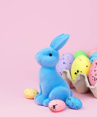 Paskalya kompozisyonu, pembe arka planda dekoratif tavşan ve paskalya yumurtaları. Uzayı kopyala Tebrik kartı. Seçici odak.