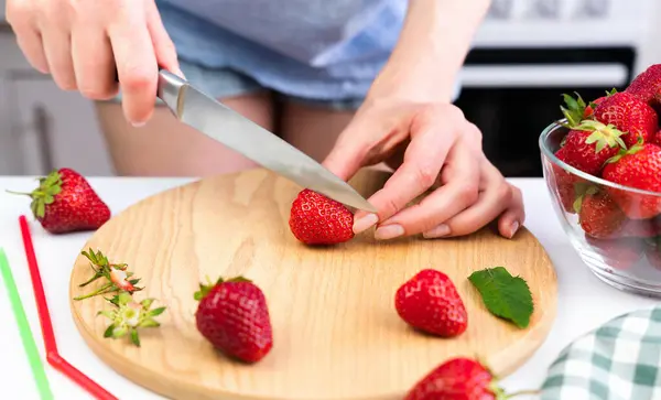 若い女性は イチゴのレモネードのためのナイフで熟したイチゴを切ります クローズアップ 選択的なフォーカス ストック画像