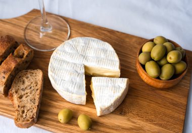 Camembert peyniri, taze çıtır baget, zeytin ve şarap. Yakın plan. Seçici odak.