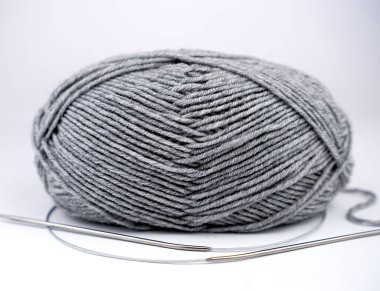 Beyaz arka planda örgü iğneleri olan gri iplik kabuğu. Yakın plan..