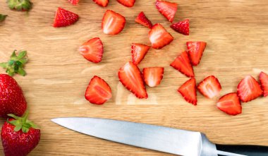 Kesme tahtasının üzerinde olgun çilek ve bıçak dilimleri. Tatlı ya da çilekli limonata hazırlıyorum. Üst Manzara. Seçici odak.