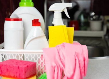 Mutfak deterjanları, temizlik malzemeleri, mutfaktaki sepetin içinde lastik eldivenler. Bahar temizliği konsepti. Yakın plan. Seçici odak.