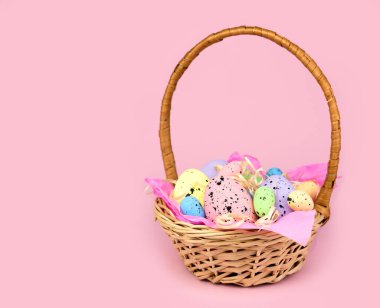 Paskalya dekoru. Hasır sepette pembe arka planda dekoratif Paskalya Yumurtaları. Seçici odak.
