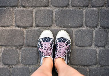 Taş yolda puantiyeli ayakkabılı kadın bacakları. Üst Manzara. Boşluğu kopyala.