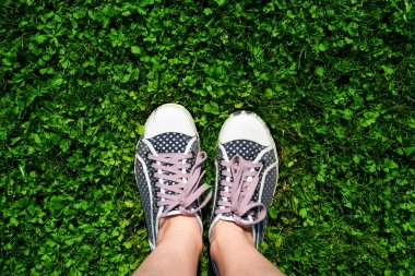 Yeşil çimlerin üzerinde kadın bacakları. Doğada yaz tatili kavramı. Üst Manzara. Boşluğu kopyala.