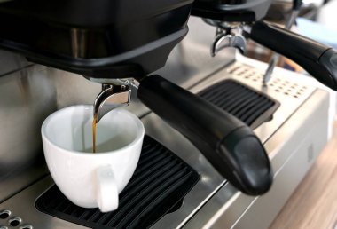 Kahve makinesi fincana taze kahve doldurur. Bir barista kahve hazırlar. Yakın plan. Seçici odak.