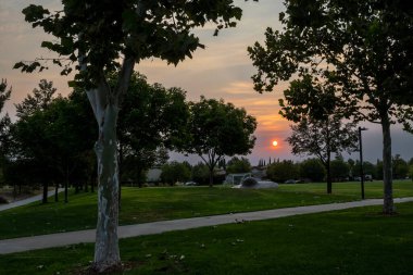 Davis, CA, USA, September 10, 2022. Sunset at the Arroyo Park wtih orange hues, showing the grass, the bike path, the soccer field