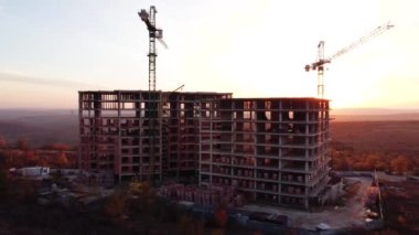 Günbatımında kuş gözü olan bir inşaat alanı. Drone 'la video çekimi. Kule vinci, kazıcı ve kum. İnşaat alanının üzerinde uçuyor. Şehirdeki fabrikanın inşaatı. Yüksek