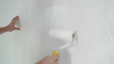 İnşaat işçisi evin ve binanın tavanını elle boyuyor. İnşaat alanında beyaz boya silindiri kullanan tamirci. Yüksek kalite 4k görüntü