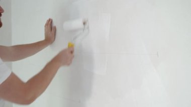 İnşaat işçisi evin ve binanın tavanını elle boyuyor. İnşaat alanında beyaz boya silindiri kullanan tamirci. Yüksek kalite 4k görüntü