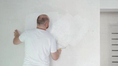 Boya silindiriyle duvarları boyayan adam. Tamirci, ev yenileme ve yenileme konsepti. Yüksek kalite 4k görüntü
