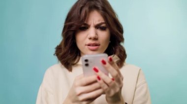 A close up portrait of a adolescent working on her freelance project, utilizing her smartphone and internet connection to collaborate with her team remotely while sitting in studio.