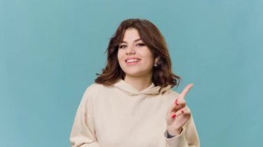 teen adolescent girl dances has joyful expression has looking at camera isolated over blue background moves with rhythm of music. copy space