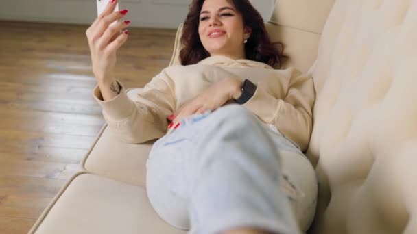 Content Teenage Student Sitting Home Her Sofa Multitasking Talking Friend — Stockvideo