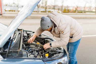 A professional technician meticulously inspects the damaged motor of a broken car, determined to find the root of the problem and provide a solution.