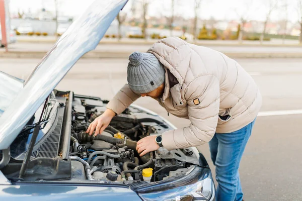 A professional technician meticulously inspects the damaged motor of a broken car, determined to find the root of the problem and provide a solution.
