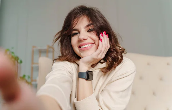 Young female with big smile sitting at living room she having fun taking selfie 