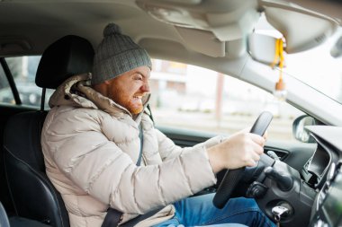 Angry driver in a traffic jam. He screams and gesticulates, Furious man gesticulates with hands and horns driving on traffic jam. Crazy driver yelling from car desperately.
