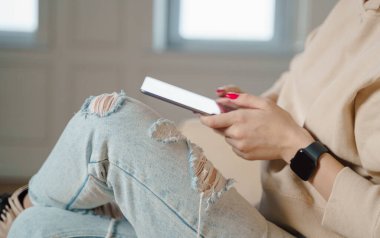 Close up of caucasian woman sitting on sofa in living room and touching tablet. High quality photo