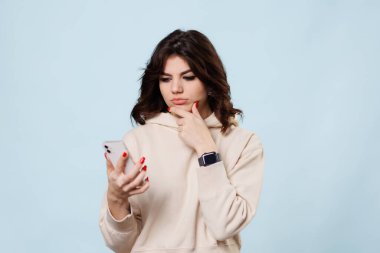Thinking girl teen looking up, Studio portrait of beautiful young woman thinking and looking upwards with smartphone. The concept of perception and reflection