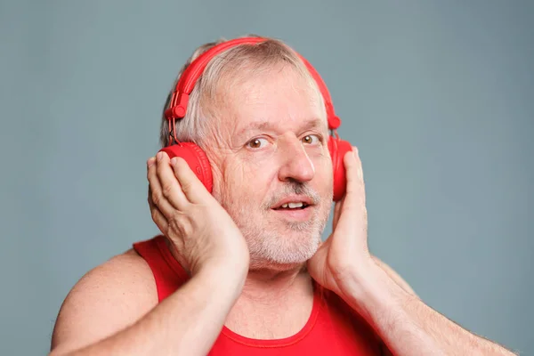 Yaşlı bir vatandaş, kulaklıklarıyla müzik dinlerken saf şaşkınlık anını yakalıyor. Gözleri şaşkınlık içinde ve yüzünde komik bir ifade var.,