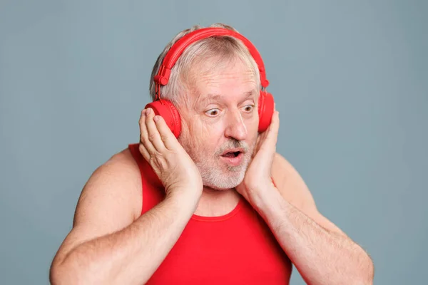 Kulaklık takan yaşlı bir adam düşüncelere dalmış müzik dinliyor ve duyduklarından bunalmış görünüyor. Yüzünde komik, komik bir ifade var, sanki...