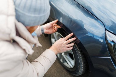 Contemplation and despair a young adult man stands beside a broken scratches car, clearly frustrated and displeased