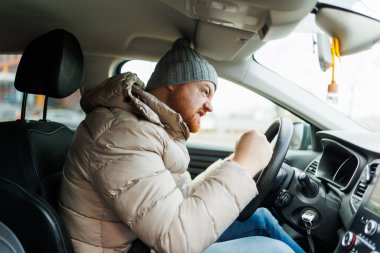 Angry driver in a traffic jam. He screams and gesticulates, Furious man gesticulates with hands and horns driving on traffic jam. Crazy driver yelling from car desperately.